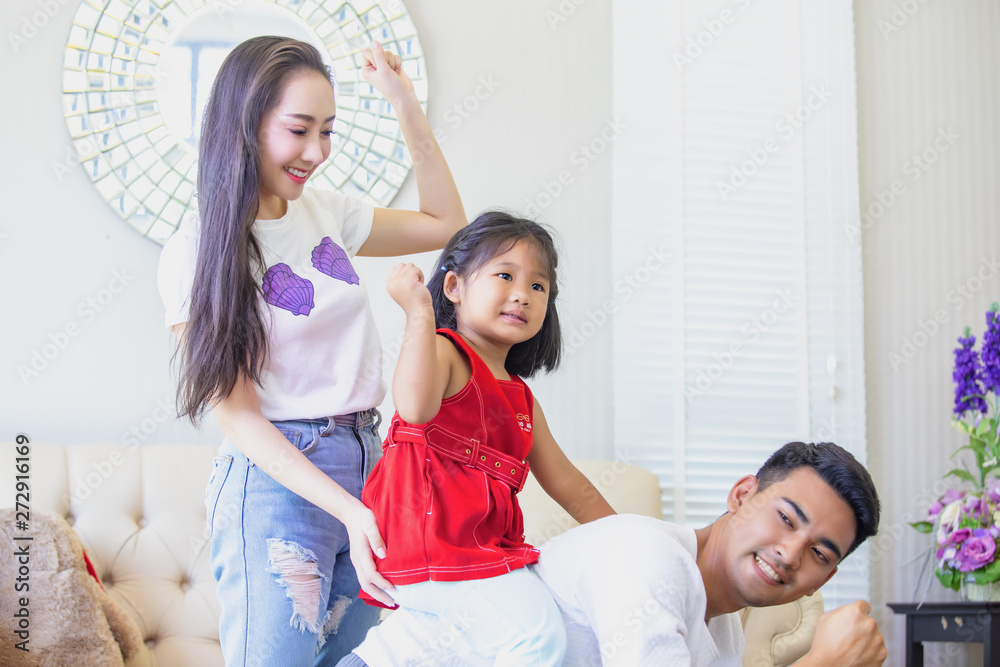 Obraz premium The Asian family is happy, the mother smiles when he sees the children and the husbands tease each other. Fun, support, the children riding the back of the father.