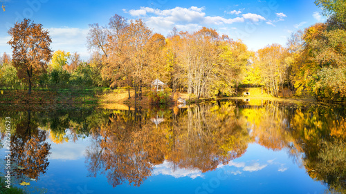 Sunny autumn landscape with blue sky over lake © sborisov