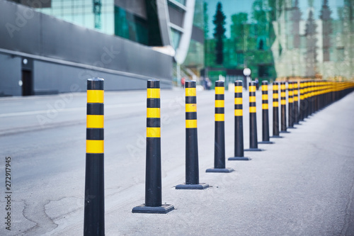 a series of striped gray and yellow signal posts on an asphalt road.