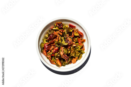 Saucer dish with granulated dried sweet pepper isolated on white background