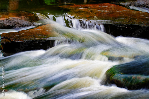 The water flows through the rocks in the stream.