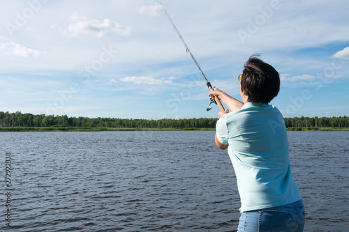 girl throws spinning in the lake to catch a fish, rear view