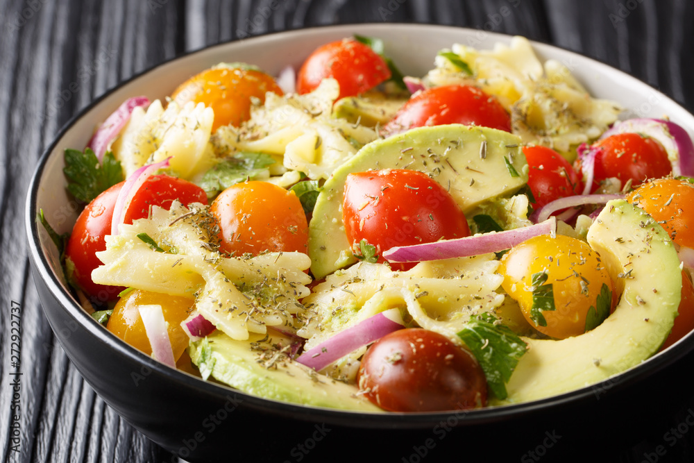 Appetizer Farfalle pasta salad with ripe avocado, onion and tomato closeup in a bowl. horizontal Appetizer Farfalle pasta salad with ripe avocado, onion and tomato closeup in a bowl. horizontal