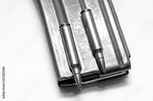 223 caliber bullets loaded into a rifle magazine with two additional bullets shot in black and white