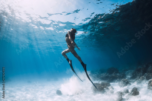 Woman freediver glides over sandy sea with fins. Freediving in ocean