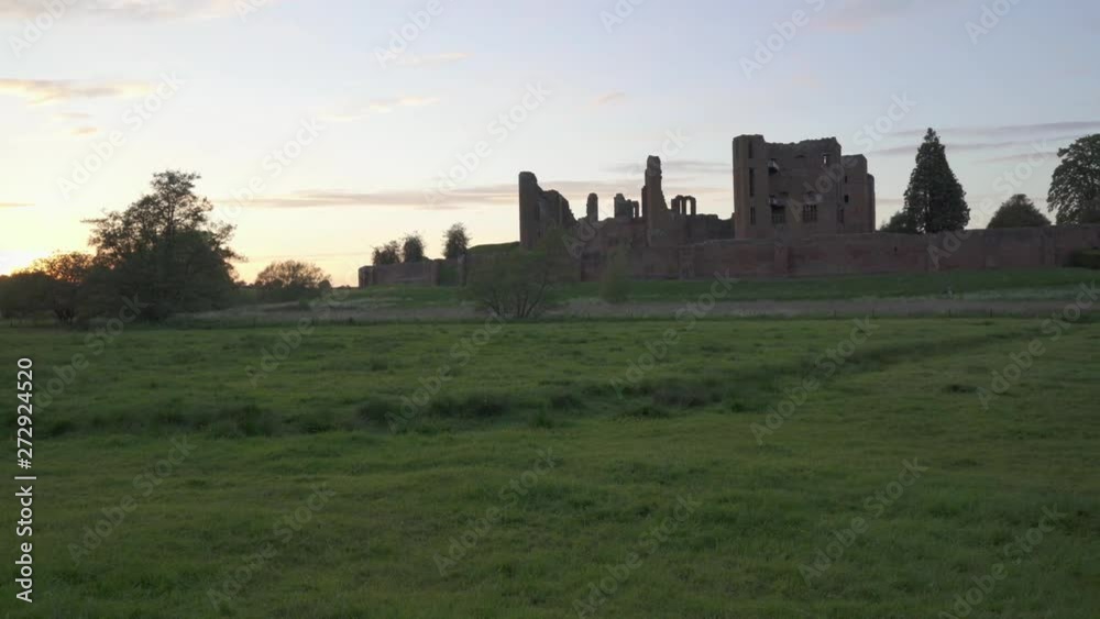 Panning shot showing Kenilworth castle in the late summer evening sunset, viewed across a meadow, Warwickshire, England Panning shot showing Kenilworth castle in the late summer evening sunset, viewed across a meadow, Warwickshire, England