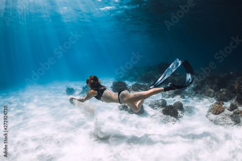 Woman freediver glides with sand over sandy sea. Freediving underwater in Hawaii