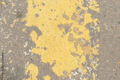 Old asphalt surface with yellow paint on it close up. Abstract background 