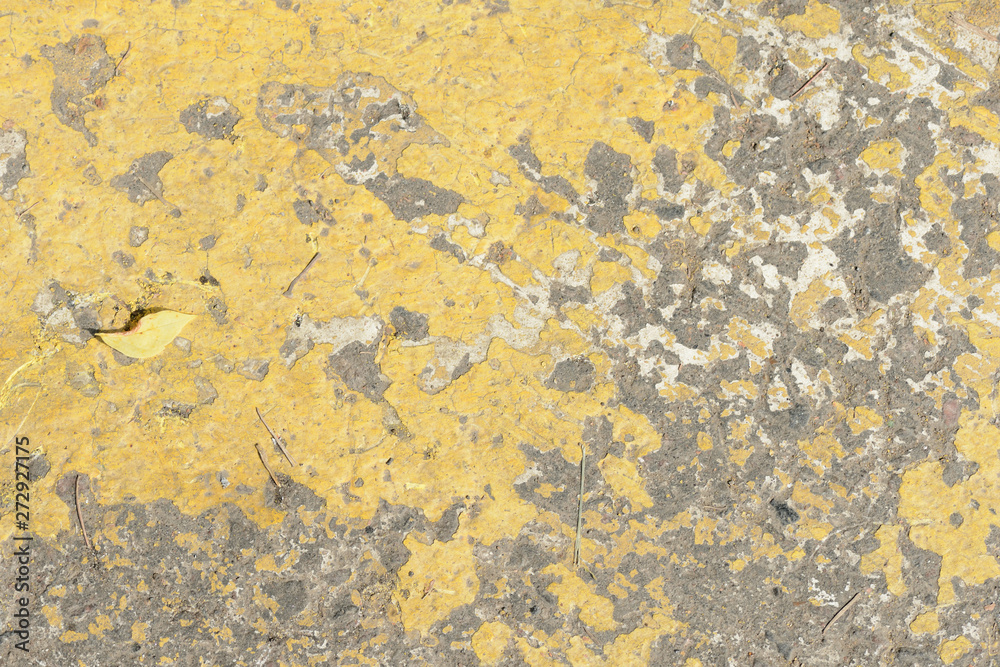 Old asphalt surface with yellow paint on it close up. Abstract background