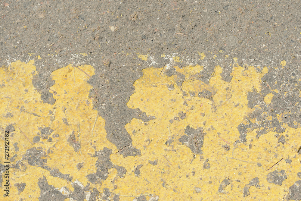 Old asphalt surface with yellow paint on it close up. Abstract background Old asphalt surface with yellow paint on it close up. Abstract background