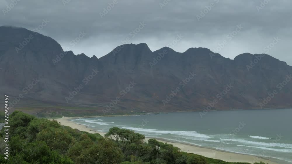 Waves running onto long stretch of pristine beach in beautiful setting, next to mountain, shot from high vantage point, South Africa.
