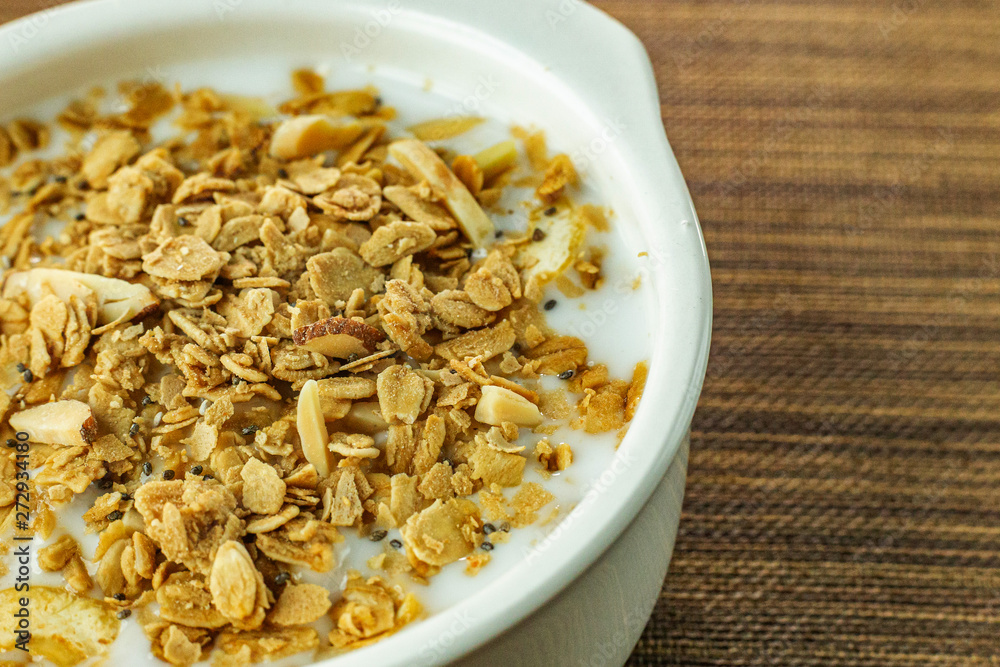 Morning food almond flakes and milk in white bowl on wood table. Morning food almond flakes and milk in white bowl on wood table.