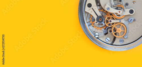 Mechanic stopwatch chronometer mechanism, spring bronze cogs wheels macro view. Shallow depth of field, selective focus. Yellow colorful background. Copy space.