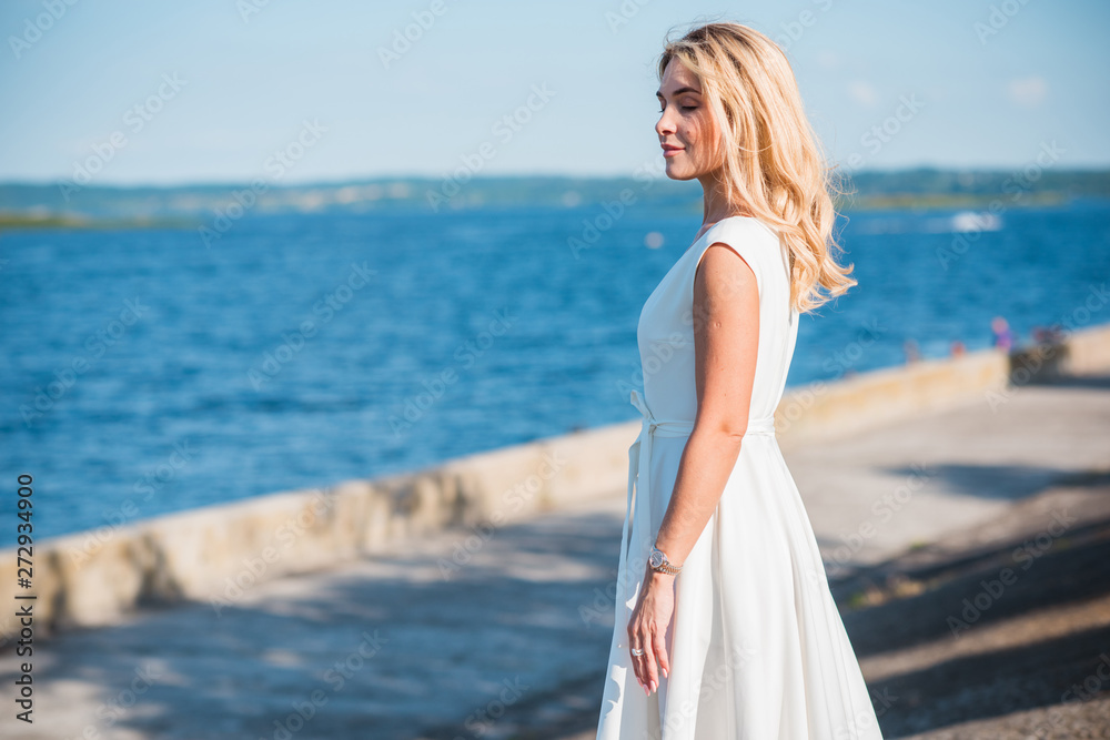 Elegant blonde hair woman in white midi dress at shore. Concept oа white code, fashionable lady, pretty dress and clothes Elegant blonde hair woman in white midi dress at shore. Concept oа white code, fashionable lady, pretty dress and clothes