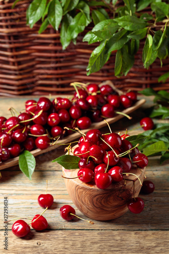 Red sweet cherry in a wooden bowl on a wooden table in garden.