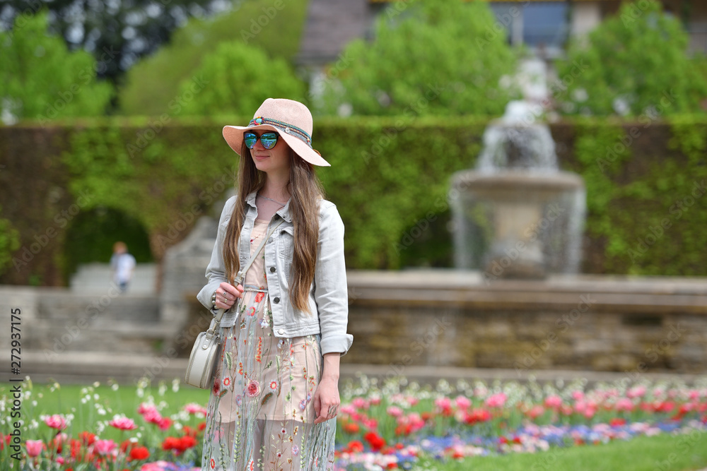 Young girl tourist in a pink dress and hat walking through the park in Europe. Tourist girl in the city of Baden-Baden