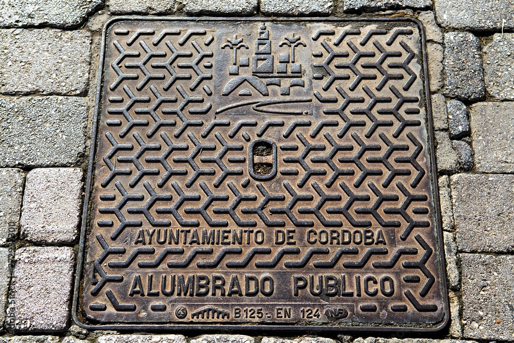 Hatch of sewage on the paving road in Cordoba, Spain. Selective focus