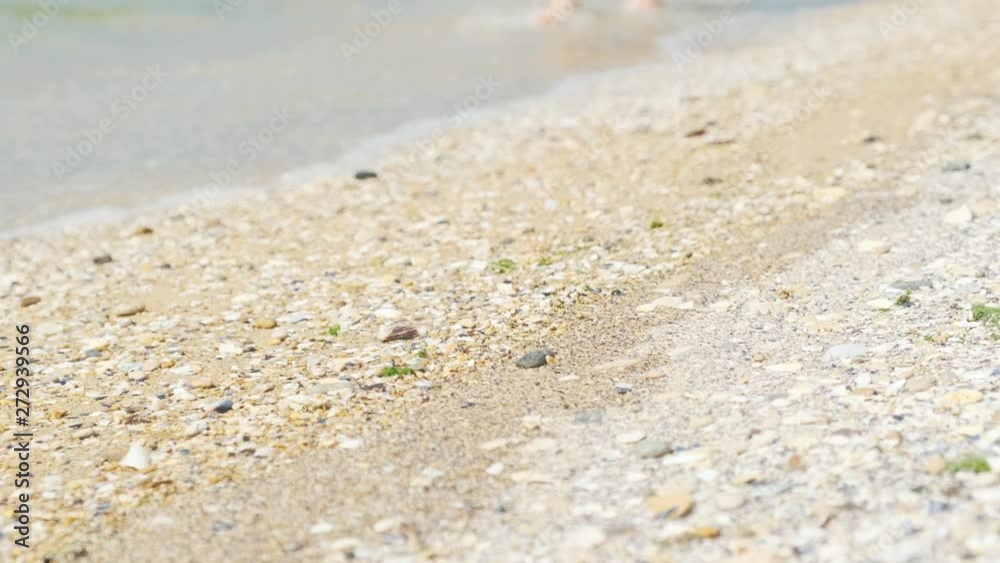 Person walking barefoot along the sunny beach. Person walking barefoot along the sunny beach.