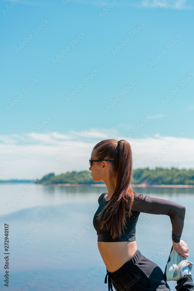 girl in uniform and sunglasses doing sports on the bank of the river. Healthy lifestyle
