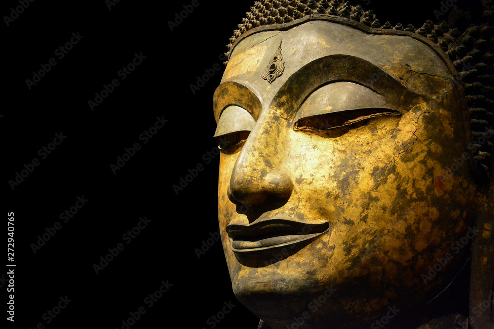 clipping path, close up of antique bronze Buddha face isolated on black background, copy space (selective focus)