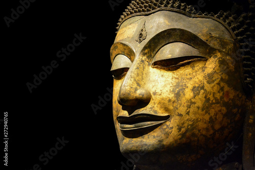clipping path, close up of antique bronze Buddha face isolated on black background, copy space (selective focus)