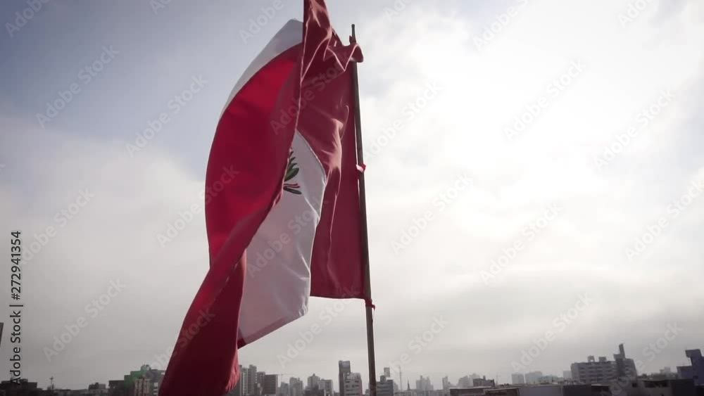 SLOW MOTION: Flag of Peru waving in wind over the cityscape of Lima