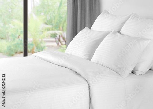 Bed with linen against a window with grey curtains