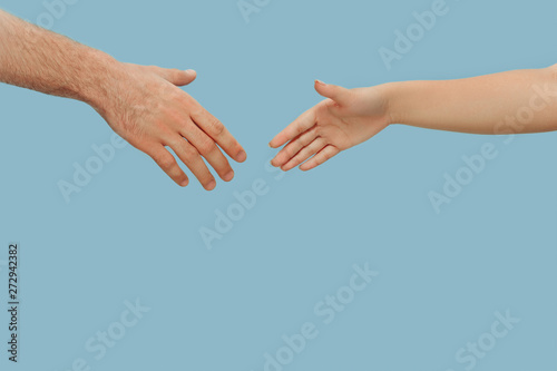 Closeup shot of human holding hands isolated on blue studio background. Concept of human relations, friendship, partnership, family. Copyspace. © master1305
