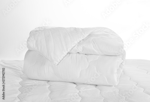 Fototapeta Naklejka Na Ścianę i Meble -  Rolled white soft duvet on the bed against the white background