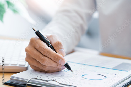 Close-up of hands Businessman reading and writing with pen signing contract over document for Completing Application Form at work in office.