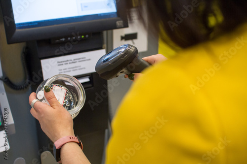 Shopping, sale, payment, consumerism and people concept. Girl scans a purchase in a store or supermarket self-service cash register photo