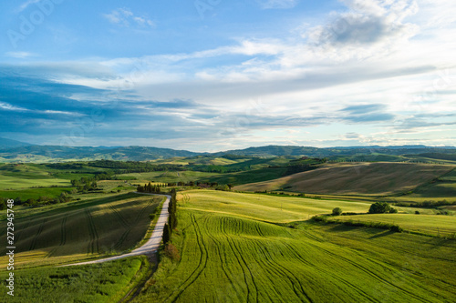 Picturesque Tuscany landscape with rolling hills, valleys, sunny fields, cypress trees along winding rural road, houses on a hill. Tourist visit in Tuscany © ZoomTeam