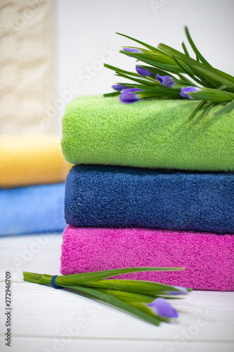 Towels in stack against the blured backdrop. Stack of green, blue, yelloy and pink towels with flowers photo