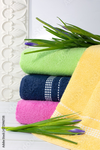 Towels in stack against the blured backdrop, stack of green, blue, yelloy and pink towels with flowers. photo