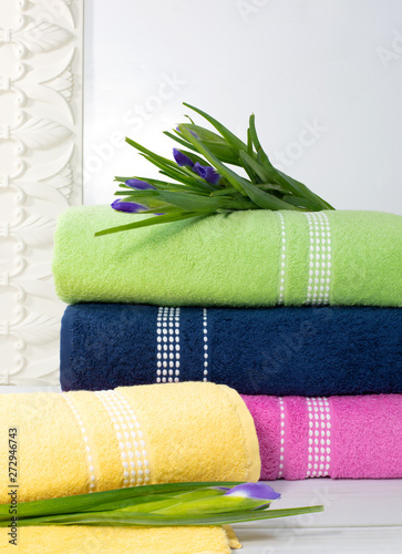 Towels in stack against the blured backdrop, stack of green, blue, yelloy and pink towels with flowers. photo