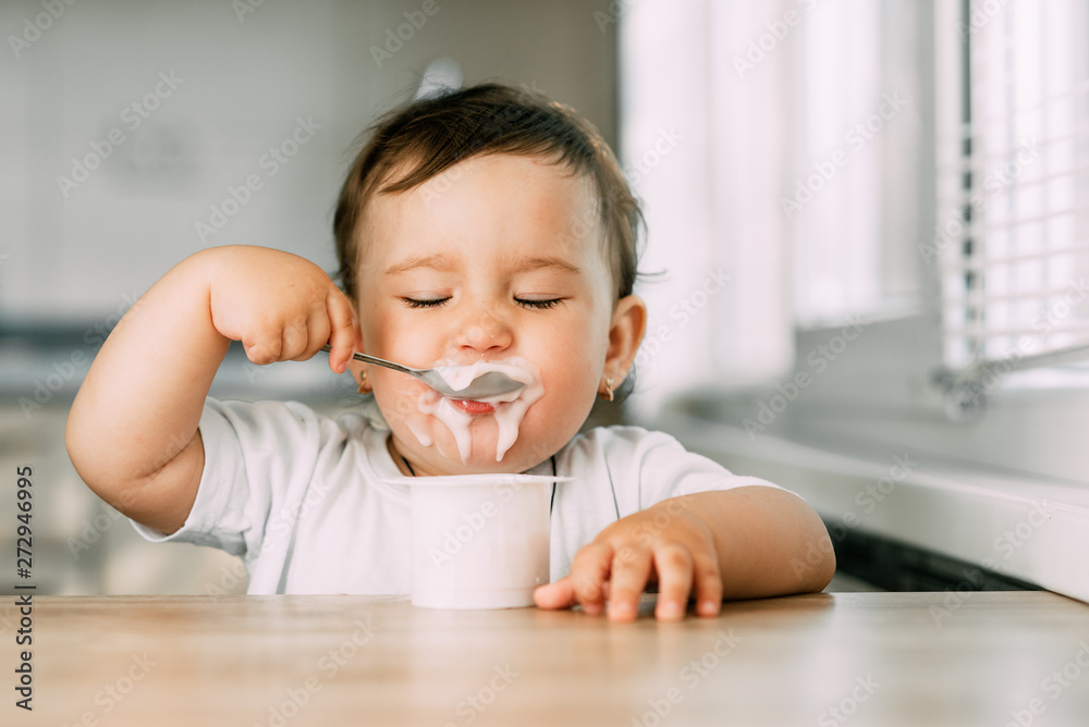 A little charming girl eats yogurt all smeared herself A little charming girl eats yogurt all smeared herself