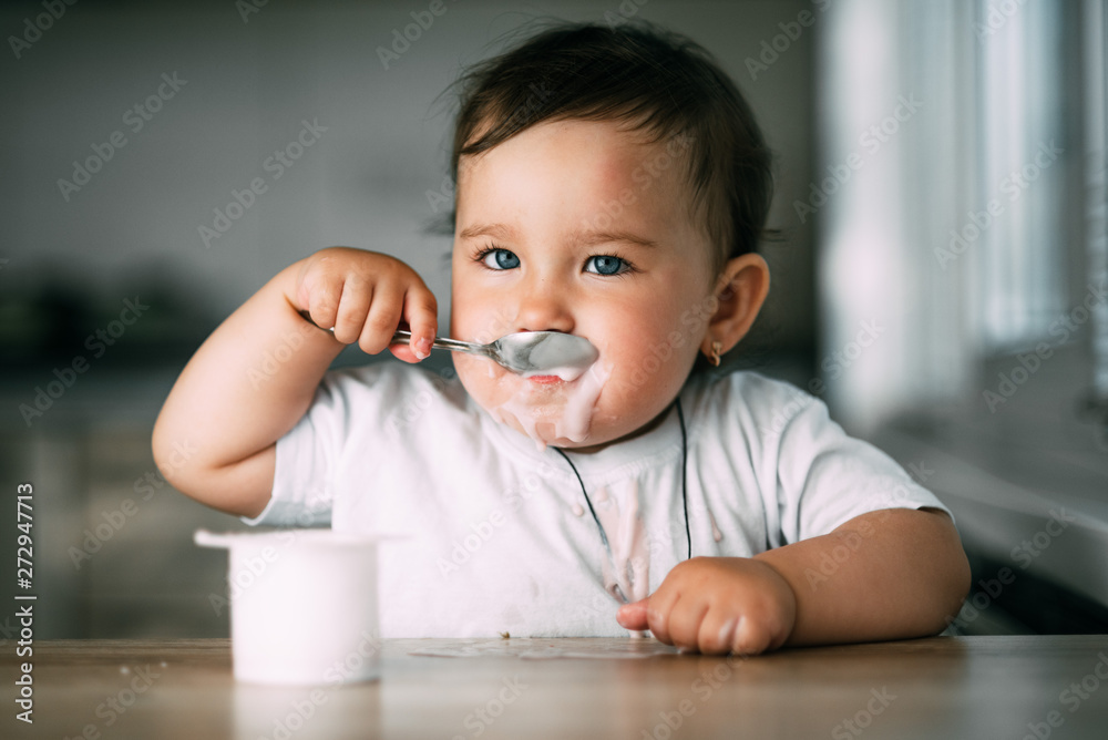 A little charming girl eats yogurt all smeared herself A little charming girl eats yogurt all smeared herself