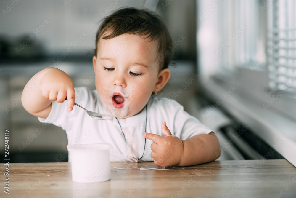 A little charming girl eats yogurt all smeared herself A little charming girl eats yogurt all smeared herself