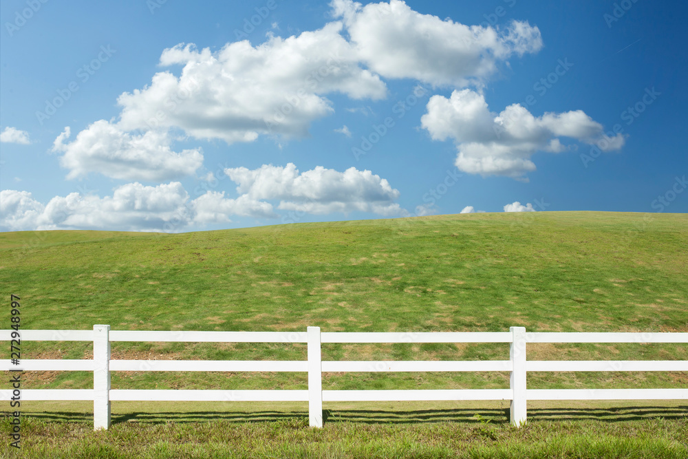 white fence in farm field with blue sky