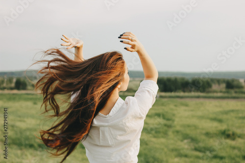 Obraz na plátně Close up portrait of beautiful carefree long hair girl in white clothes in field, view from back