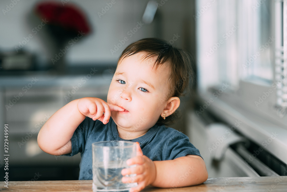 Cute little girl sitting in baby chair and drinking water Cute little girl sitting in baby chair and drinking water