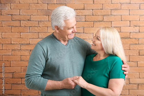 Portrait of happy mature couple against brick wall