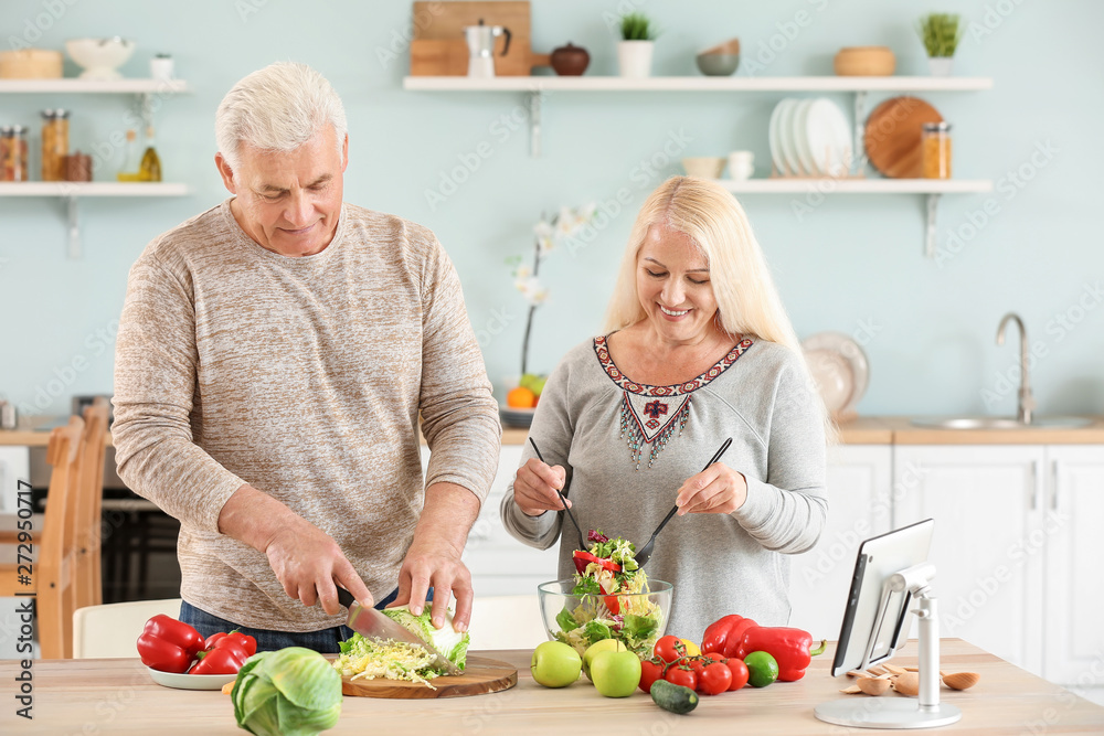 Portrait of happy mature couple cooking in kitchen Portrait of happy mature couple cooking in kitchen