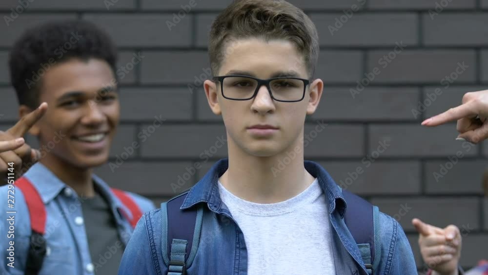 Abused schoolboy looking with hope to camera, group of students mocking him Abused schoolboy looking with hope to camera, group of students mocking him