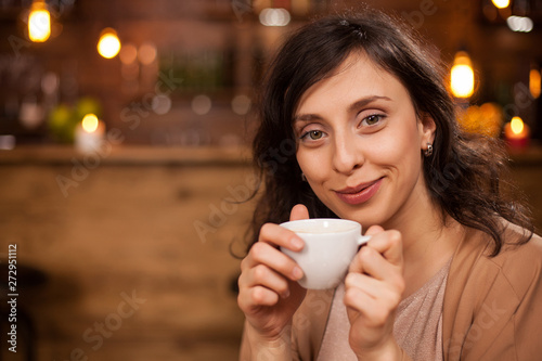 Attractive caucasian woman smilling and looking at the camera with a coffee cup in hand