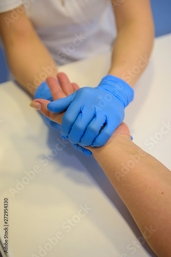 Hand care at the Spa. Hand massage close-up. Specialist in blue medical gloves makes stroking therapeutic massage of hands.