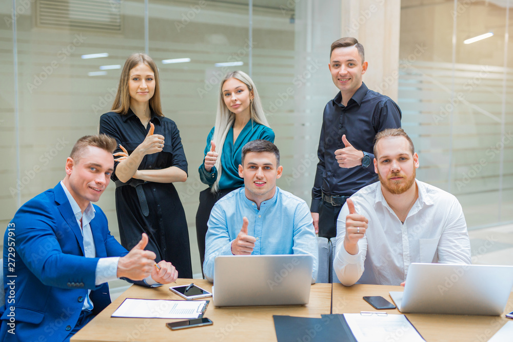 Obraz premium team of young professionals men and women at work in the office with a gesture of hands