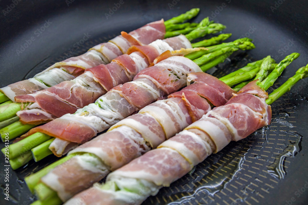 Tasty bacon wrapped asparagus in frying pan