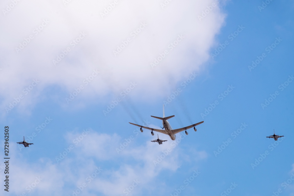 Military tanker aircraft (refueler) and fighter jets fly on blue sky and clouds background Military tanker aircraft (refueler) and fighter jets fly on blue sky and clouds background