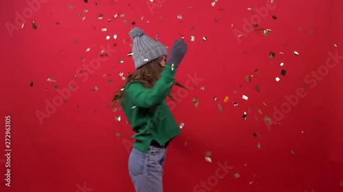 girl throws gold confetti on a red background photo